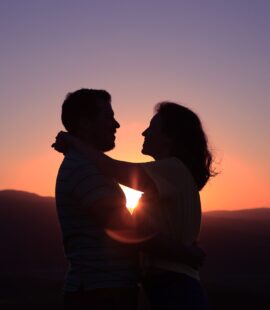 silhouettes of two people a man and woman embracing in the purple and orange sunset, finding love after divorce